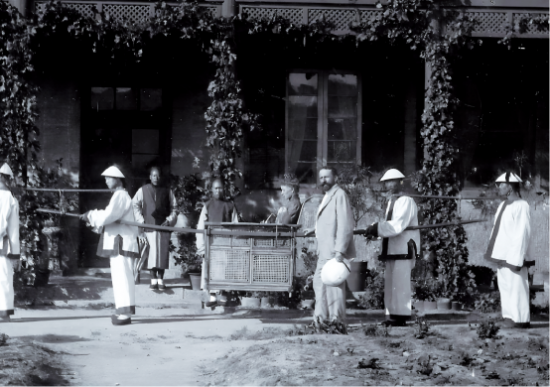巴保男爵(穿西装者)和夫人赫米娜(坐轿者)在烟台期间的一张留影，大约于1913 年拍摄于张裕公司老厂房前